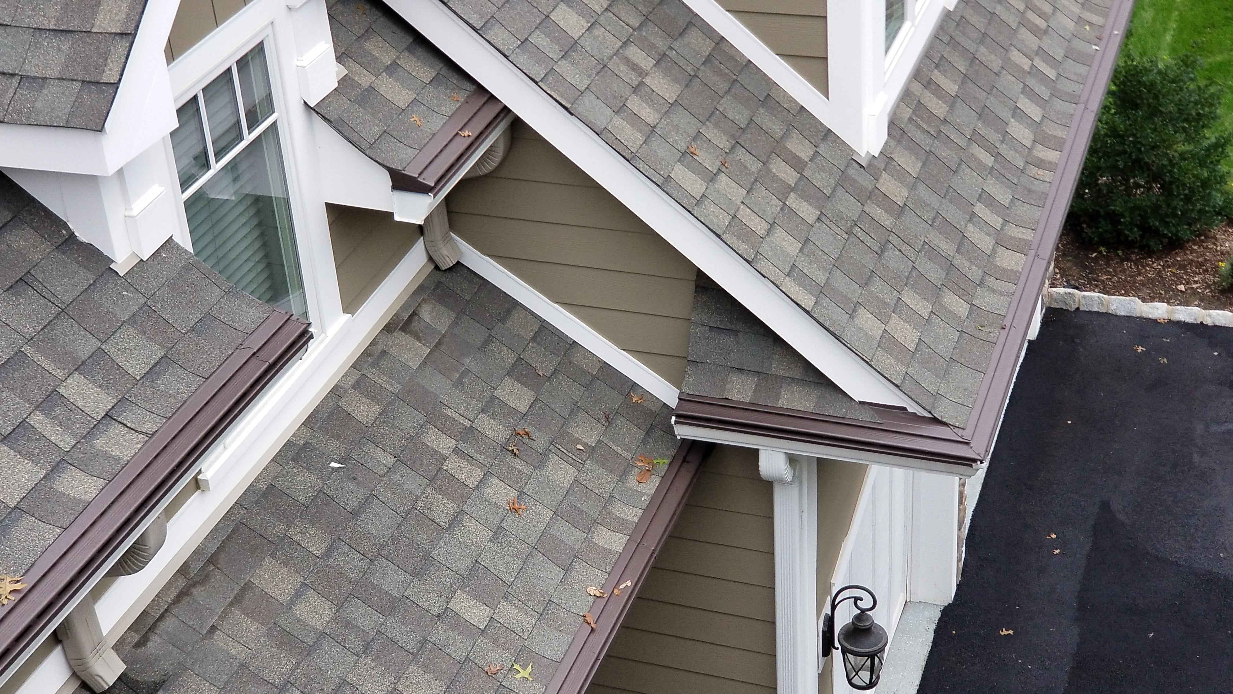 Gutter guard system installed at the roof edge showing controlled water flow into gutters