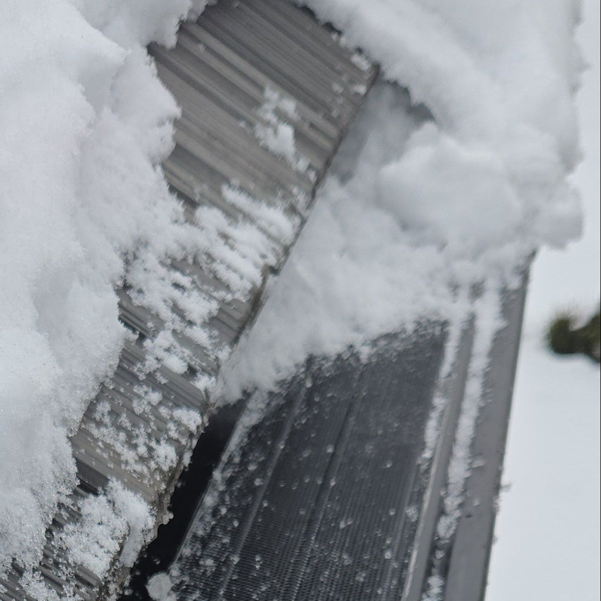 Aluminum micro-mesh gutter guard installed inside the gutter showing winter snow and ice performance