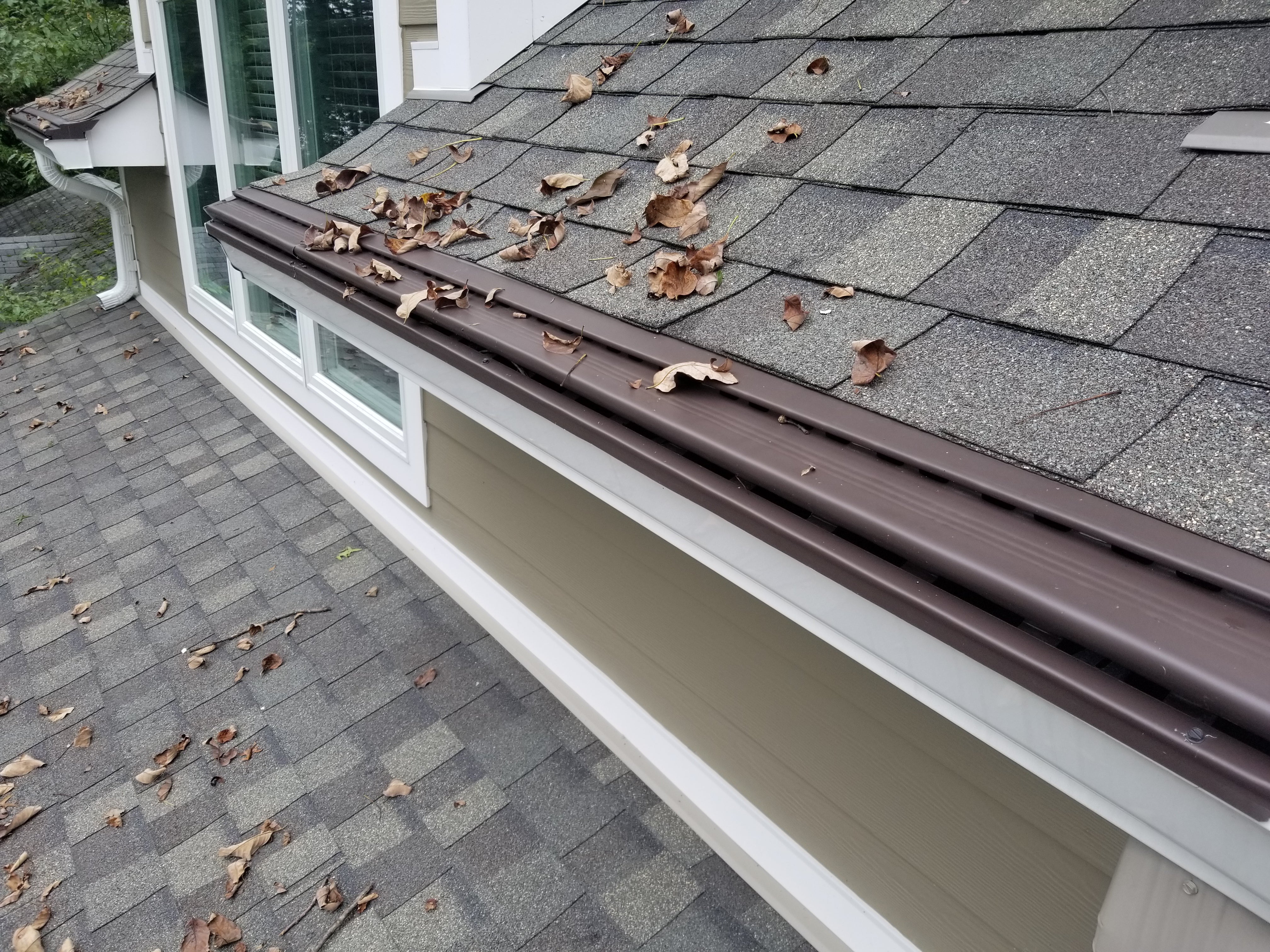 Solid surface gutter guard allowing leaves to shed off the roof edge while water enters the gutter