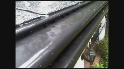 Gutter guard installed at roof edge showing rainwater flow while leaves shed off the surface